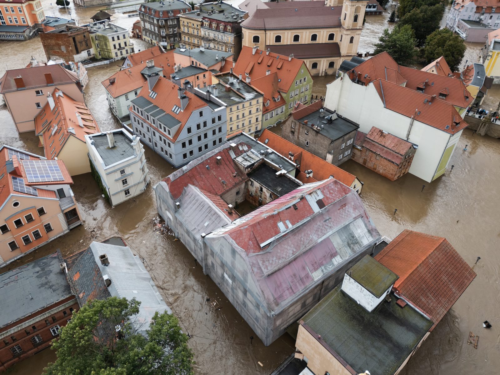 Streets between old houses under flood water, seen from the air