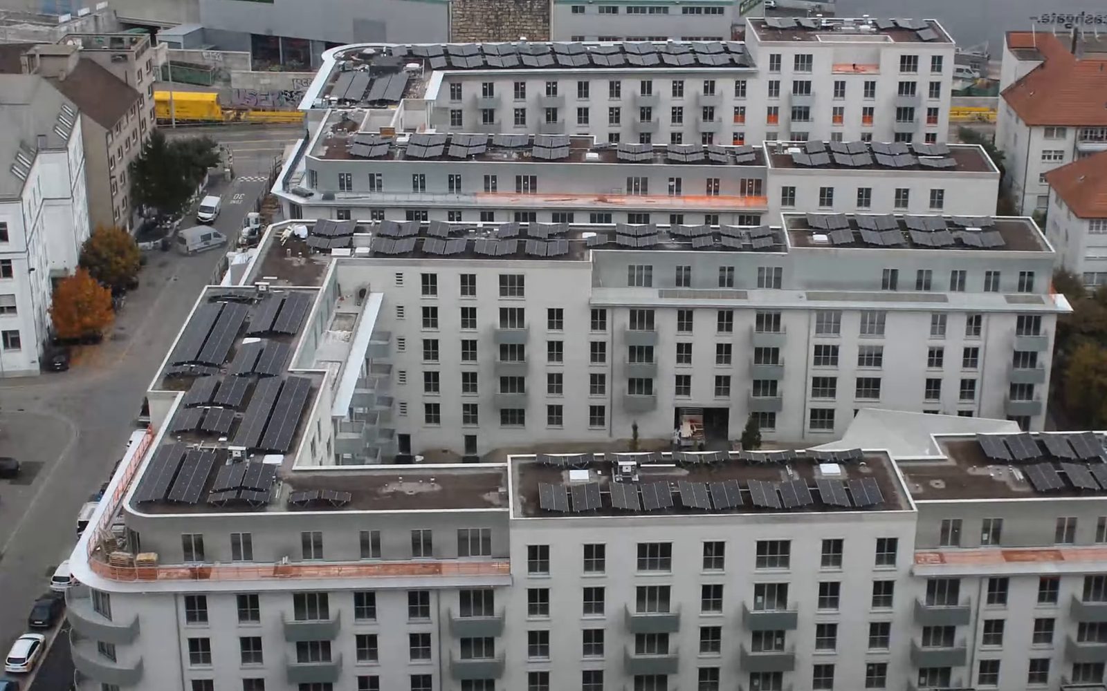 The same spot in 2022: a finished six-storey block of flats with solar panels on its roofs