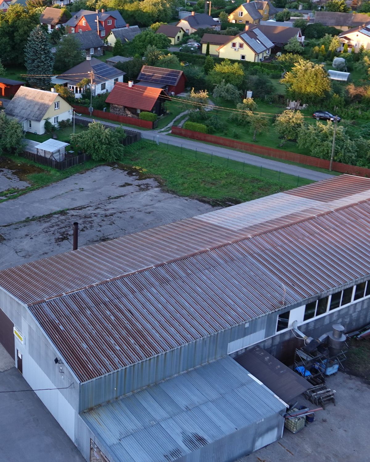 Worn metal roofs of workshops and houses in Ülejõe, Pärnu, seen from a drone