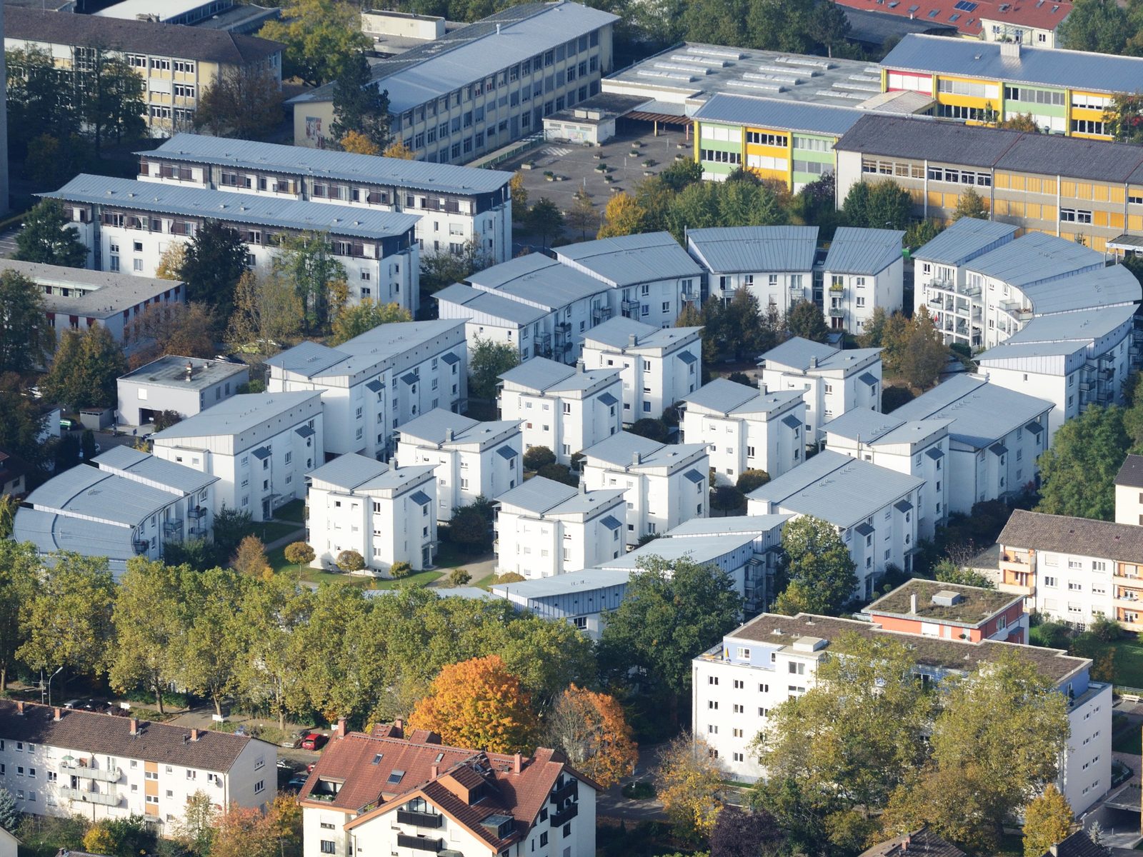 Apartment blocks with flat roofs and balconies among trees, seen from the air